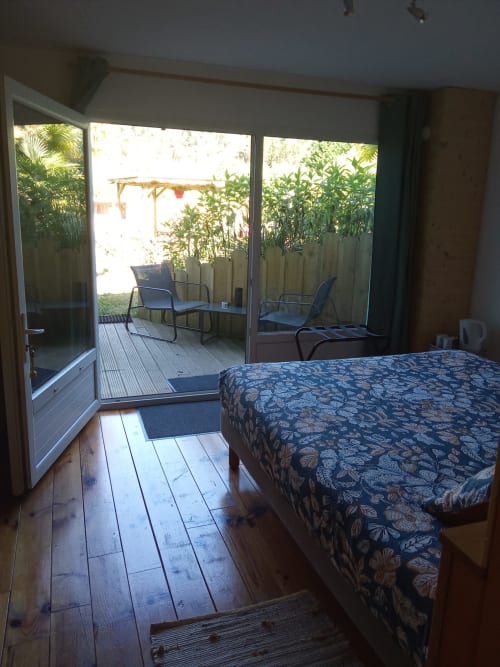 Chambre avec lit à motifs ouvrant sur la terrasse jardin avec chaises au Mas des Landes, Vielle-Saint-Girons