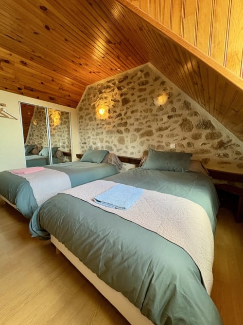 Zweibettzimmer in Lo Soulenquo in Golinhac mit Steinmauern, Holzdecke und Bergblick