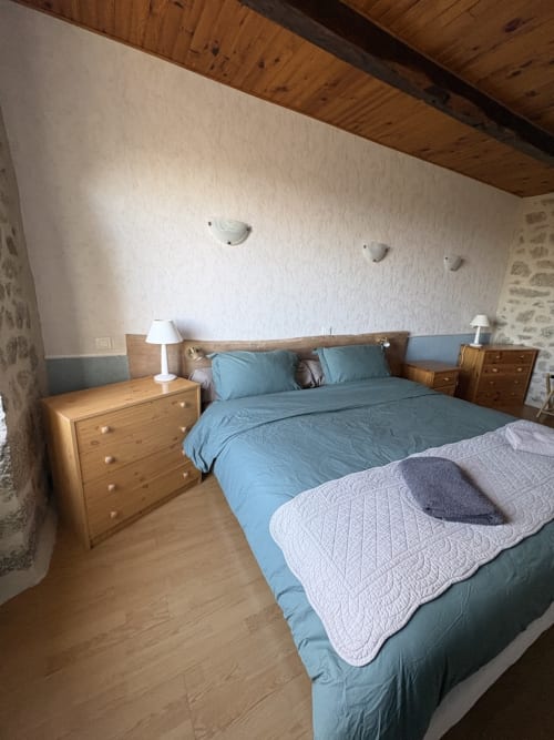 Chambre avec literie bleue et mobilier en bois à la maison d'hôtes Lo Soulenquo à Golinhac, France