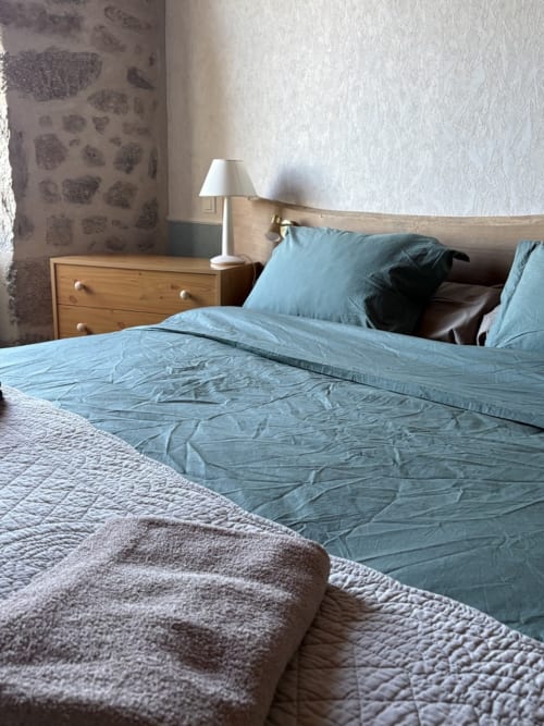 Chambre douillette de la maison d'hôtes Lo Soulenquo à Golinhac avec literie bleue, mobilier en bois et vue sur les montagnes