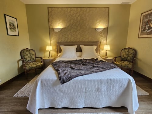 Chambre élégante du Château de Ribourdin avec lit double, mobilier d'époque et murs jaune chaud à Chevannes.