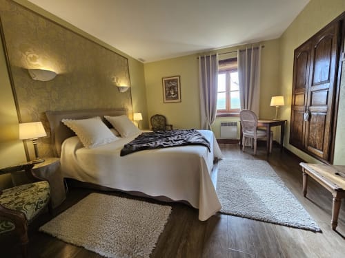 Chambre élégante au Château de Ribourdin : lit queen-size, murs jaunes, mobilier en bois et vue sur le jardin à Chevannes