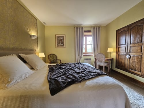 Élégante chambre au Château de Ribourdin aux murs jaunes, vue sur le jardin et décor français classique