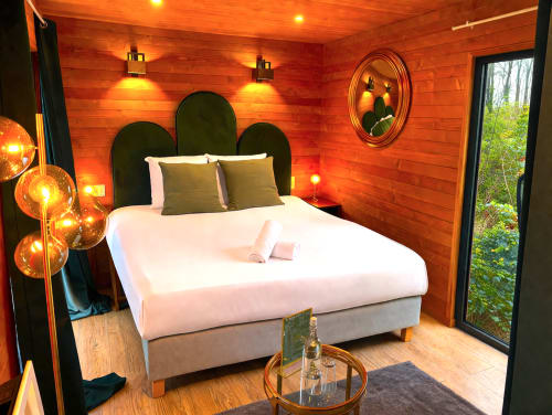 Cozy bedroom at Les Lodges de Vaugrigneuse with warm wood walls, black headboard, and ambient lighting in Vaugrigneuse