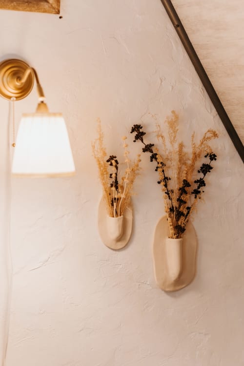 Décoration murale minimaliste au gîte La Grange Marguerite aux Granges de Pil Bara avec fleurs séchées en vases crème et laiton