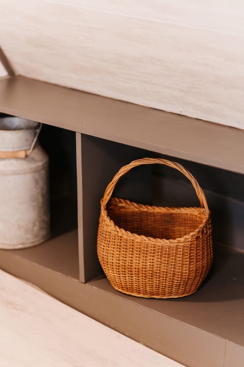 Panier en osier tressé rangé sous l'étagère en bois dans le gîte La Grange Marguerite aux Granges De Pil Bara, Langoat
