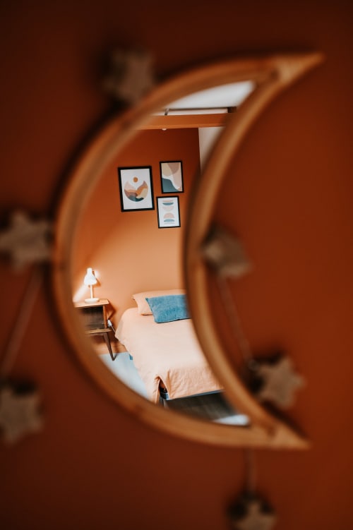 Vue de chambre à travers une porte en arche en bois au gîte Les Granges De Pil Bara à Langoat, France, avec lit, lampe de bureau et