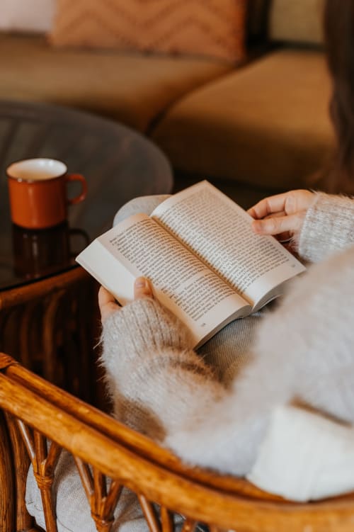 Hôte lisant un livre avec une tasse de café dans une chambre confortable des Granges De Pil Bara, Langoat