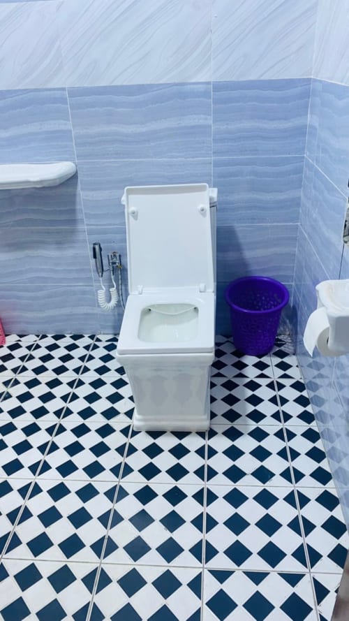 Modern bathroom at Kylian Appart Hotel Brazzaville with white toilet, blue tile walls, and black-white geometric floor