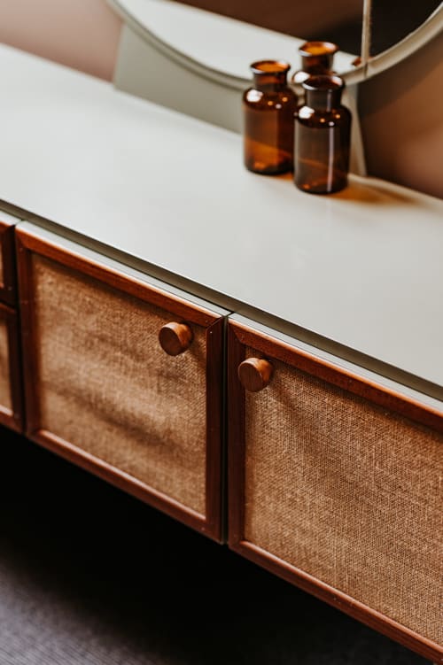 Élégant meuble en bois avec panneaux en tissu et bouteilles en verre ambré aux Granges de Pil Bara à Langoat