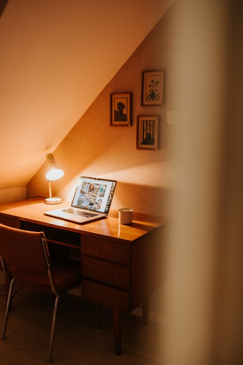 Espace de travail douillet dans le grenier des Granges De Pil Bara, Langoat avec ordinateur portable, lampe de bureau et art botanique encadré