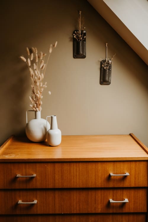 Décoration minimaliste de la chambre du gîte Les Granges De Pil Bara avec vases blancs et fleurs séchées sur commode en bois