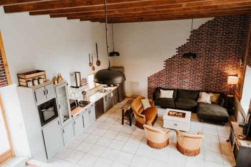 Intérieur de gîte ouvert aux Granges De Pil Bara avec cuisine, séjour, poutres apparentes et mur de cheminée en brique