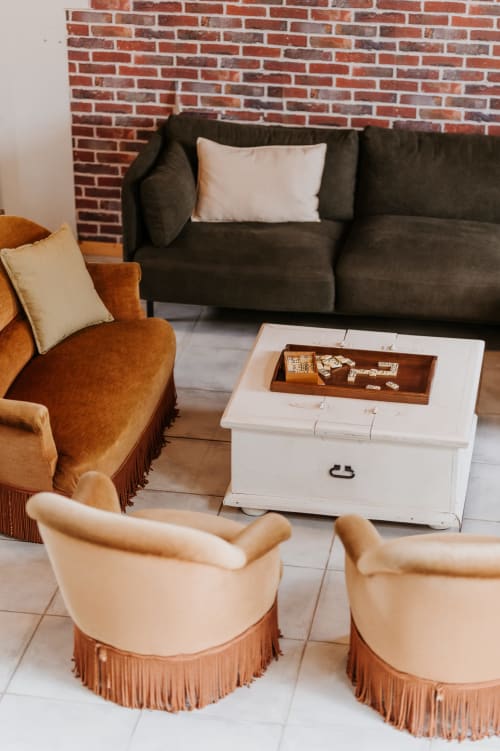 Élégant salon aux Granges de Pil Bara avec sièges vintage, table coffre blanche et foyer en brique