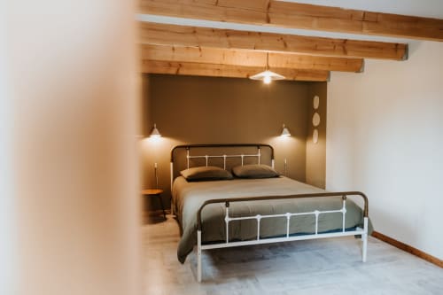 Chambre moderne du gîte La Grange Sarrasin aux Granges De Pil Bara, Langoat, avec poutres apparentes et lit en métal