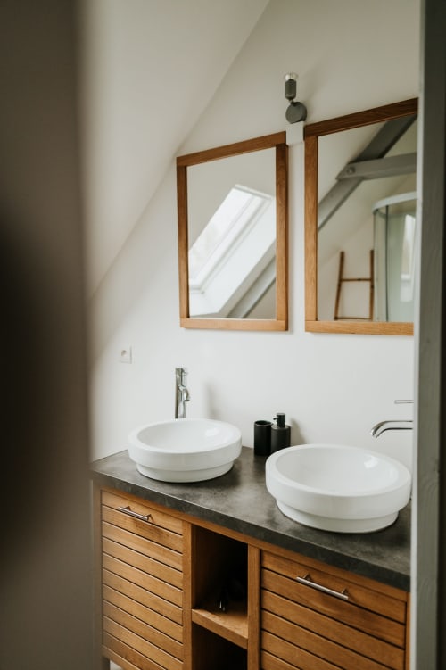 Vanité de salle de bain moderne avec deux vasques blanches, meubles en bois et miroirs encadrés au gîte Les Granges De Pil Bara