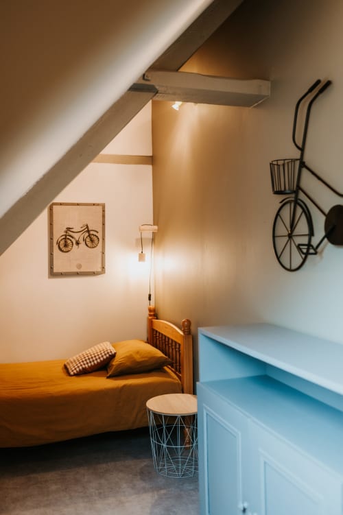 Chambre douillette sous les toits aux Granges De Pil Bara à Langoat avec lit en bois, décoration vélo et mobilier moderne