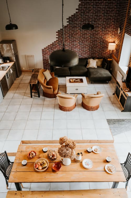 Intérieur de cottage ouvert aux Granges De Pil Bara avec table à manger, luminaires suspendus noirs, mur de brique et espace détente