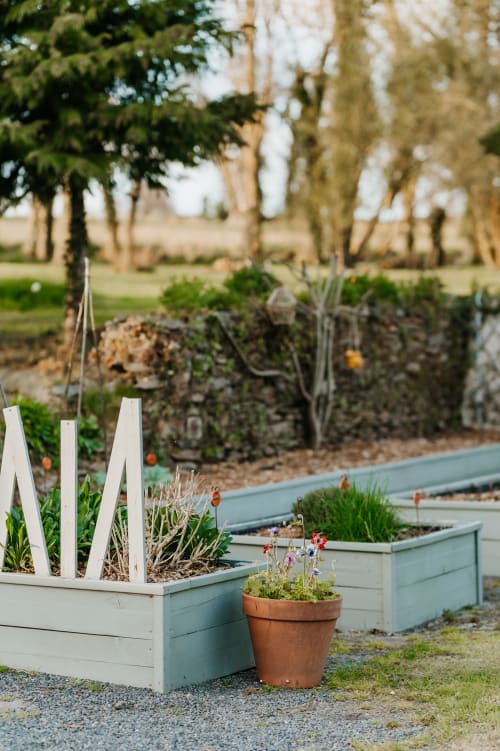 Carrés potagers surélevés à bordures blanches et fleurs en pots aux Granges De Pil Bara à Langoat, France