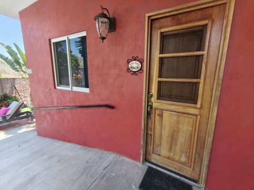 Exterior de estuco rojo del Casa Punta Perula Boutique Hotel con puerta de madera, ventana y farol en Punta Perula, México