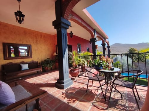 Terraza de Casa Punta Perula con asientos, plantas tropicales, vista a la piscina y paisaje montañoso en Punta Perula, México