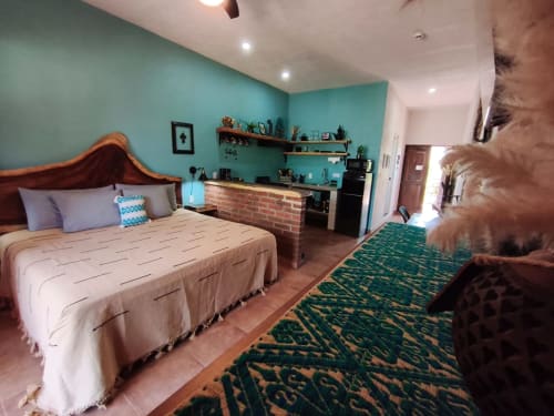 Habitación turquesa en Casa Punta Perula Boutique Hotel con cama de madera, pared de ladrillo y piso de terracota
