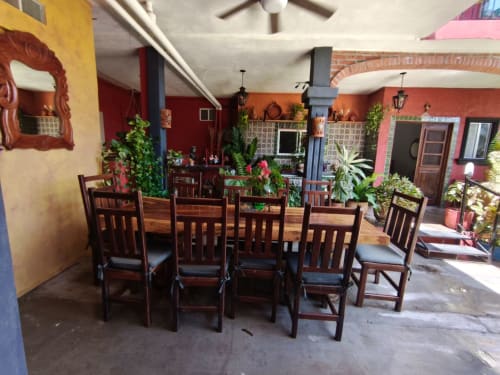 Colorida zona de comedor al aire libre en Casa Punta Perula con sillas de madera, plantas, y paredes rojo y amarillo en Punta Perula,