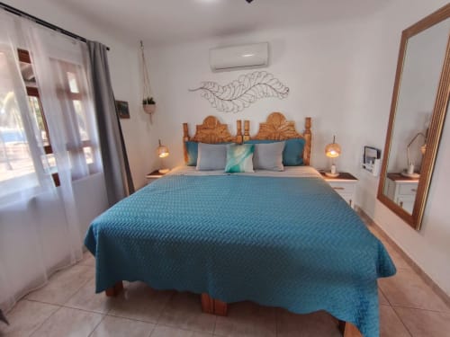 Dormitorio luminoso en Casa Punta Perula con cama turquesa, cabecera de madera y decoración costera en Punta Perula, México