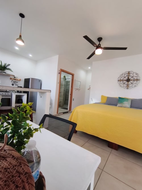 Dormitorio estudio en Casa Punta Perula Boutique Hotel con cama amarilla, cocineta y ventilador de techo en Punta Perula