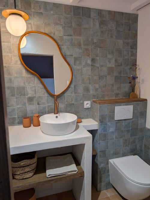 Modern bathroom at Domaine de Pelican with wood-framed organic mirror, vessel sink, and tiled walls in Gignac