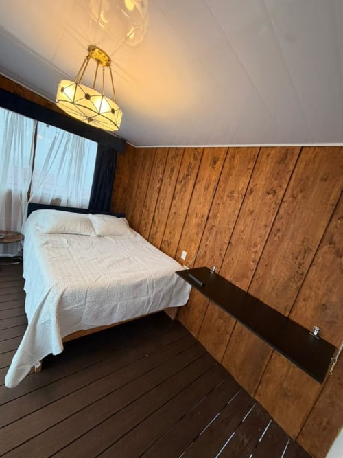 Modern bedroom at Chalets Vistas del Poas with queen bed, wood paneling, geometric pendant light, and mountain views