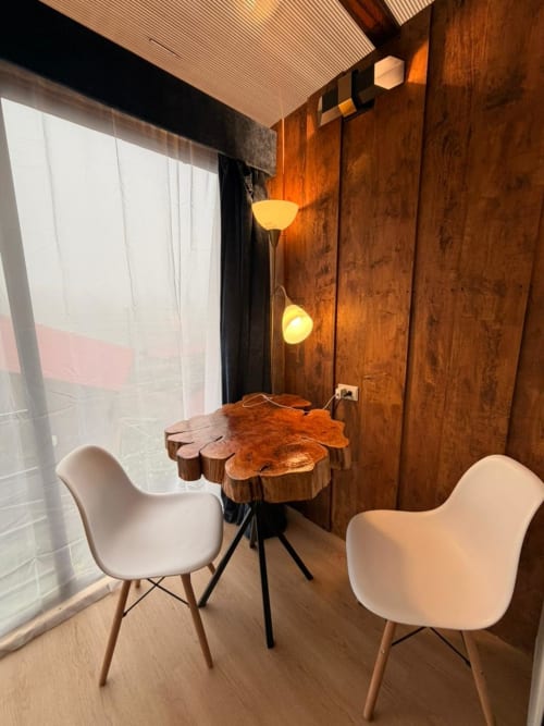 Modern chalet interior at Chalets Vistas del Poas with white chairs, wooden accent table, warm lighting, and mountain views