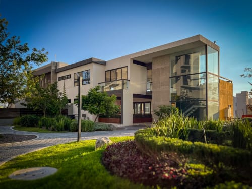 Modern architectural home at Living UP in Juriquilla, Mexico with glass facade, landscaped gardens, and contemporary design