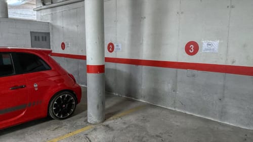 Red car parked in numbered garage space 1 at Finques Garcia Enrich apartment complex in Palafrugell with free parking