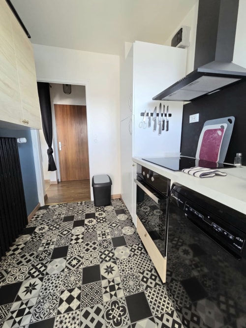 Cuisine moderne de l'appartement Le Sympa chez NN Patrimoine, Douvaine, avec électroménagers noirs et carrelage à motifs