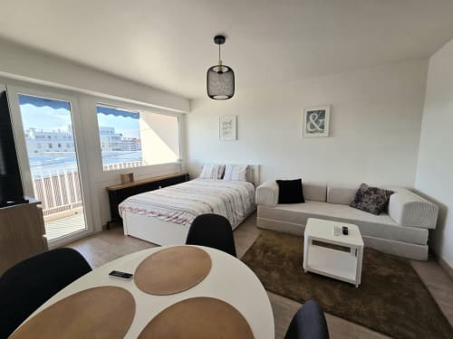 Studio moderne à Douvaine avec lit, canapé, coin repas et vue sur la ville depuis le balcon