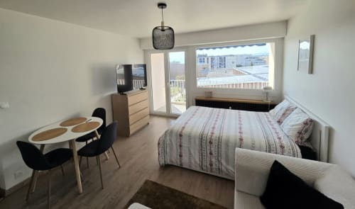 Chambre moderne du NN Patrimoine à Douvaine avec vue sur la ville, lit, TV, table à manger et accès balcon