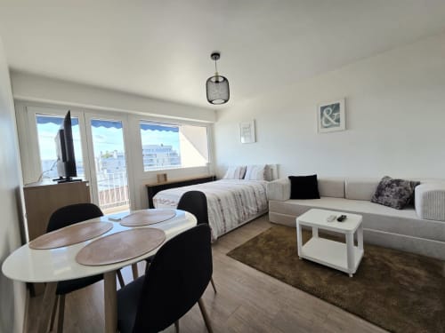 Studio moderne chez NN Patrimoine à Douvaine avec lit, canapé, coin repas et vue sur la ville depuis le balcon