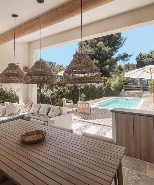 Patio de villa moderne avec luminaires suspendus tressés, coin détente et vue sur la piscine à La Conciergerie De Franck, Boissieres