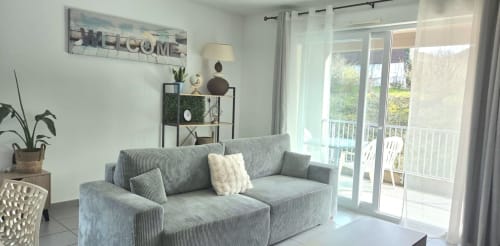 Salon lumineux avec canapé gris, portes sur jardin et décoration accueillante à l'appartement NN Patrimoine Douvaine