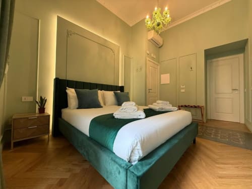 Spacious double bedroom at Residenza Seconnino Naples with green upholstered bed, wooden floors, and modern amenities
