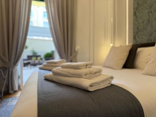 Lussuosa camera d'hotel presso Residenza Secondino Napoli con asciugamani piegati, vista dal balcone e arredi eleganti