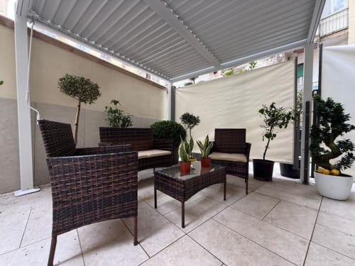 Balcone coperto moderno con mobili in rattan e piante in vaso a Residenza Seconnino, Napoli