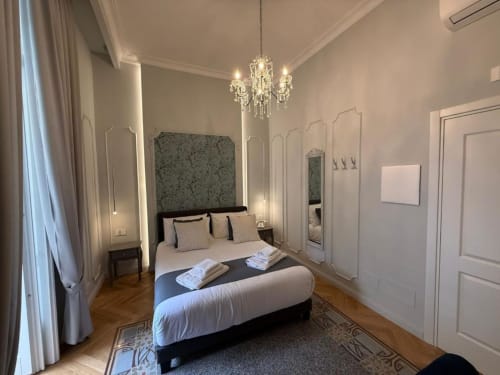 Elegante camera matrimoniale presso la Residenza Seconnino di Napoli con lampadario, pavimenti in legno e comfort moderni
