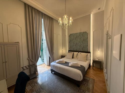 Elegante camera matrimoniale della Residenza Seconnino Napoli con lampadario, vista balcone e arredamento classico