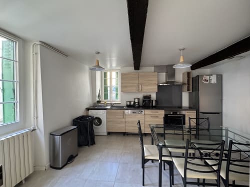 Cuisine moderne et salle à manger du gîte Verniolle avec meubles en bois, appareils en acier inoxydable et table à manger noire