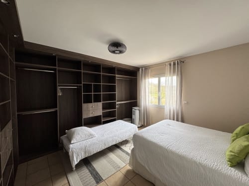 Chambre spacieuse au Gîte du Mercadal avec deux lits, armoire intégrée en bois foncé, vue sur les montagnes et équipements modernes