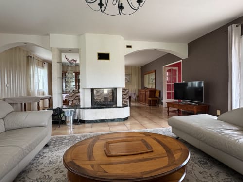 Spacieux séjour du Gîte du Mercadal aux Pujols avec cheminée, sièges en cuir, table basse en bois et télévision