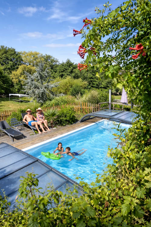 Famille profitant de la piscine du Petit Moulin B&B à Pouzauges, France, entourée de jardins luxuriants