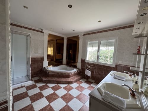 Salle de bain luxueuse du gîte Mercadal avec bain à remous d'angle, carrelage en marbre et vues sur les montagnes